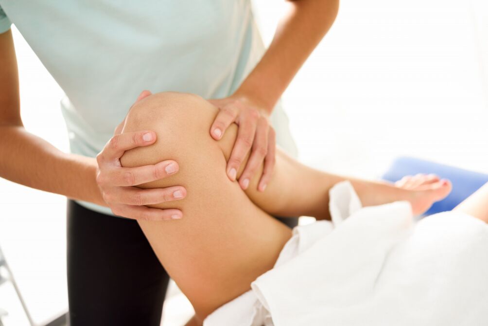 A specialist makes therapeutic massage with knee arthrosis